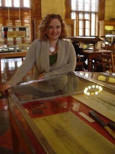 Katie Pierce stands by one the cabinets displaying drawings and artifacts from the Karl Kamrath Collection.